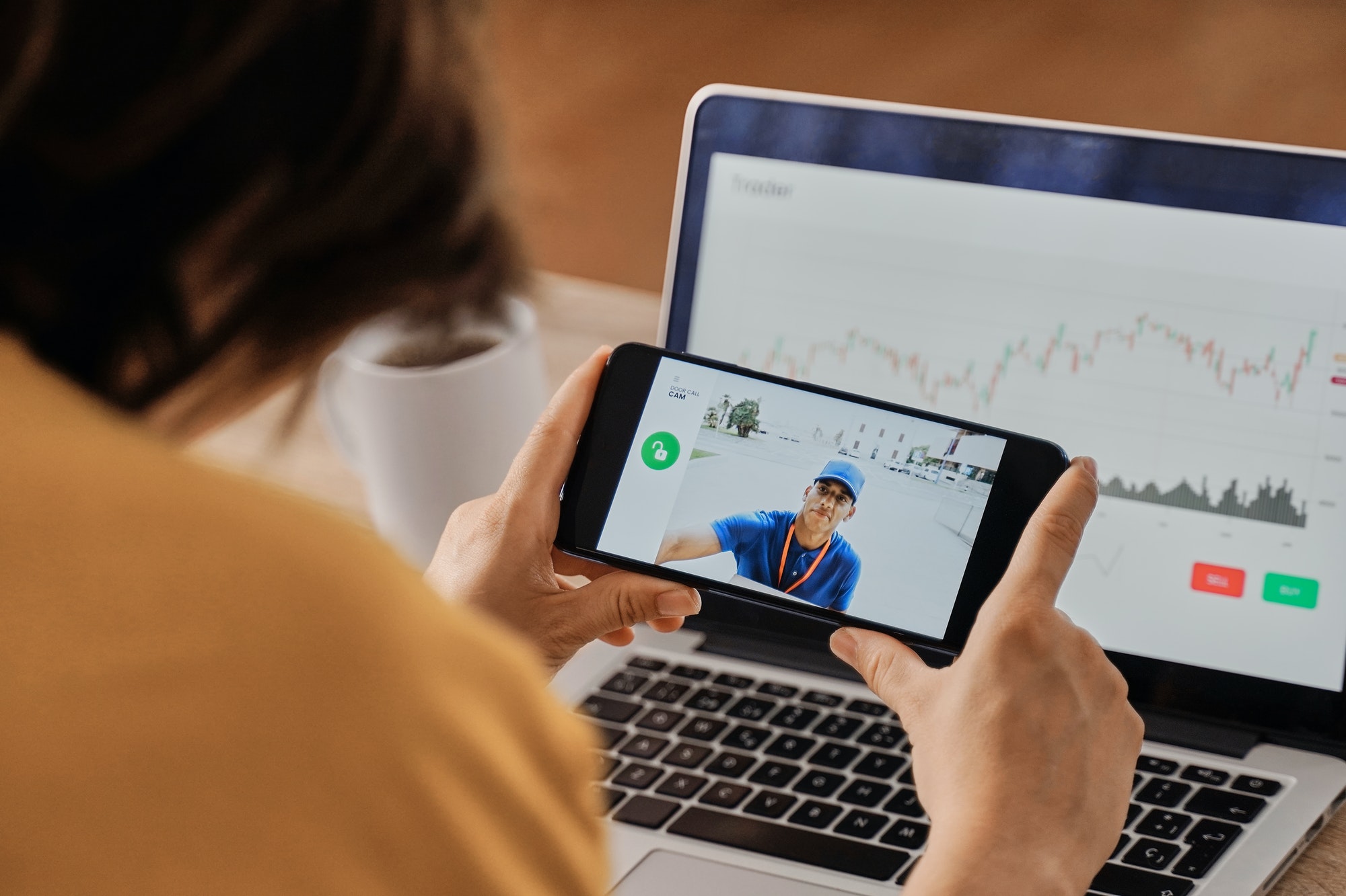 woman-watching-delivery-man-on-security-camera-video-on-mobile-phone-while-working-at-home-office.jpg