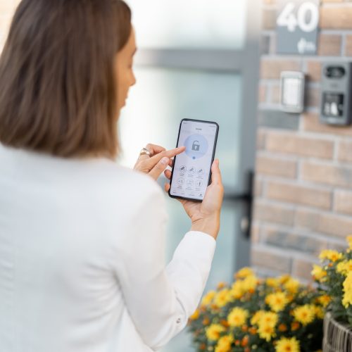 female-closes-the-door-or-turns-on-the-house-alarm-with-phone.jpg